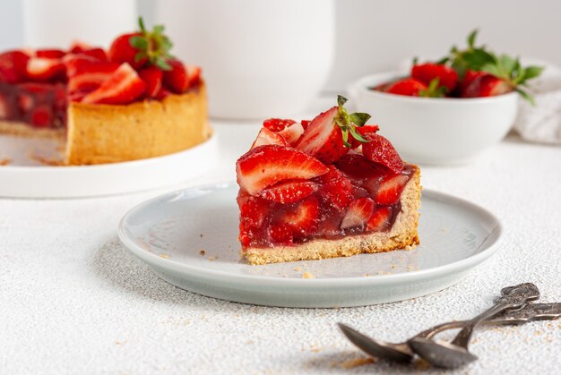 A piece of summer pie with fresh strawberry on a plate, ready to eat