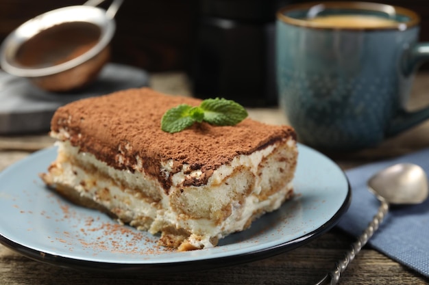 piece of tasty tiramisu on wooden table closeup