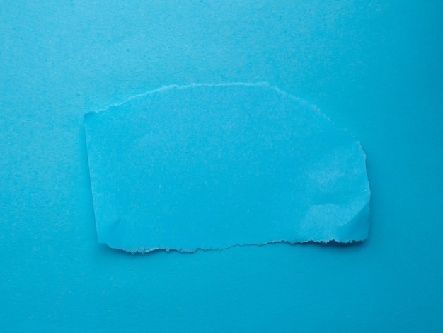 A piece of torn blue paper with a torn corner.