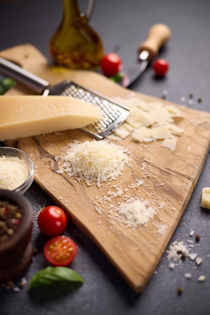 Photo piece of traditional italian parmesan hard cheese on a wooden cutting board at domestic kitchen