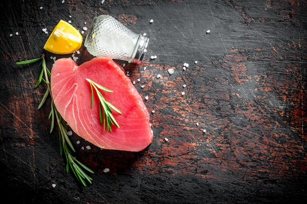 Foto pezzo di bistecca di tonno crudo con spezie rosmarino e limone