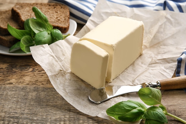 Piece of unwrapped butter and knife on wooden table