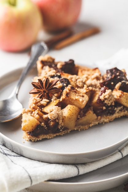 Piece of vegan apple pie with cinnamon, white background. Vegan food concept.