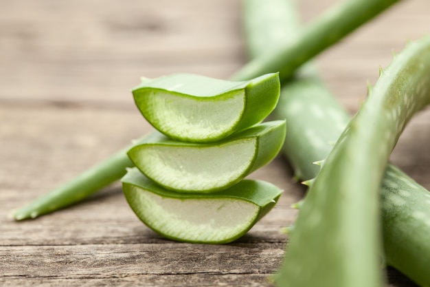 Pieces of aloe vera with pulp on a wooden background.