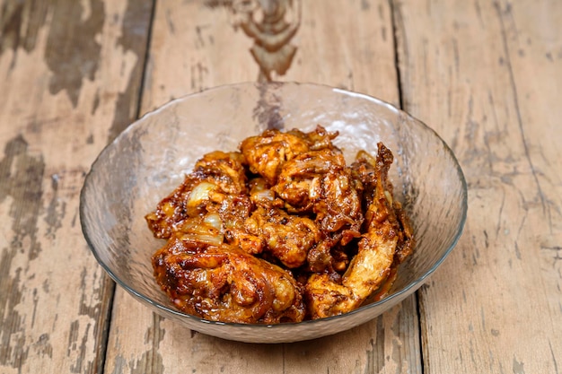 Pieces of baked chicken in sauce in a glass plate on a wooden table