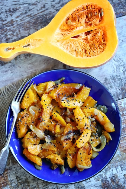 Pezzi di zucca al forno con cipolle su un piatto blu