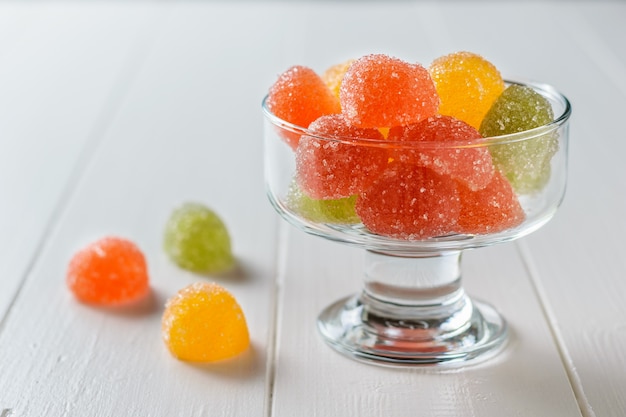 Pieces of beautiful marmalade in a glass bowl on a white table. Delicious sweets made of jelly with sugar.