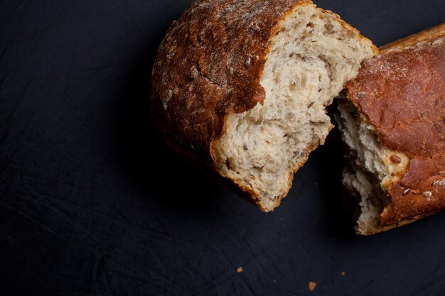 Foto pezzi di pane con crusca e semi, su fondo scuro. foto ravvicinata, messa a fuoco morbida. cibo salutare.