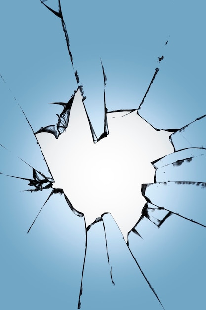 Pieces of broken glass with a hole in the center on a blue background Texture of cracks on the wind