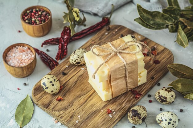 Pieces of cheese in paper on wooden board on the light gray concrete table surface Copy space for you text