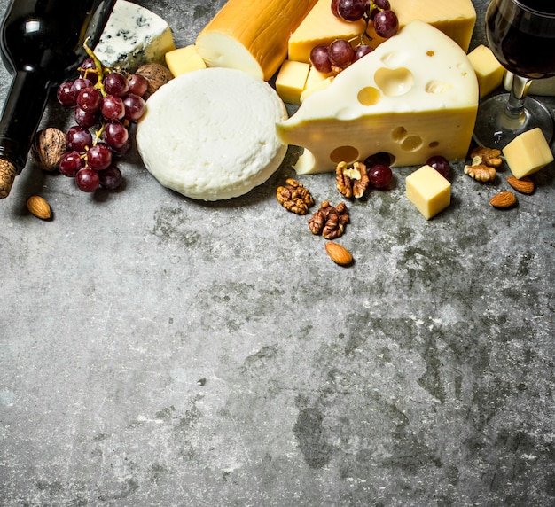 Pieces of cheese with red wine and nuts. On the stone table.