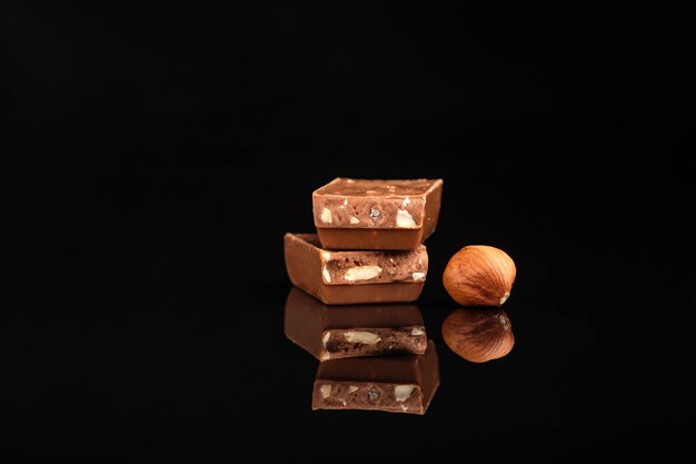 Pieces of chocolate and nuts on a wooden table on black isolated
