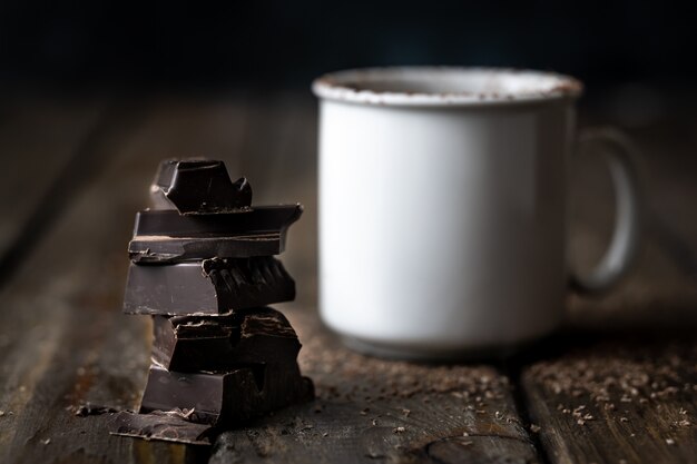 Photo pieces of chocolate piled up with white ceramic cup
