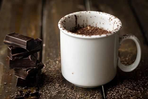 Foto pezzi di cioccolato ammucchiati con una tazza di ceramica bianca