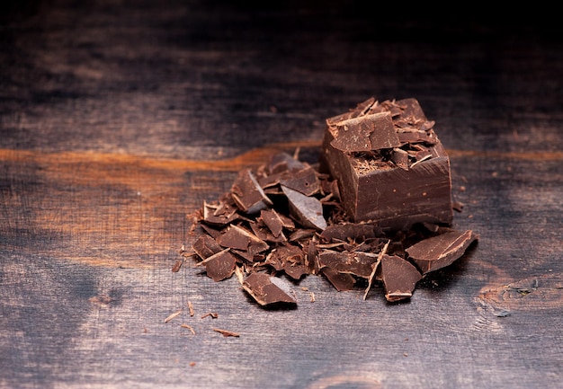 Pieces and chopped chocolate on a dark wooden background