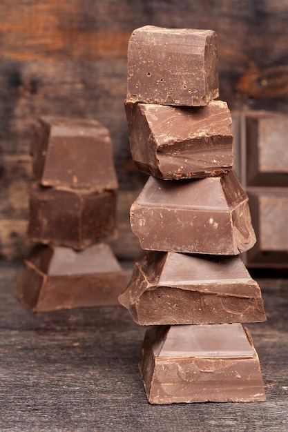 Pieces chopped dark chocolate on wooden background