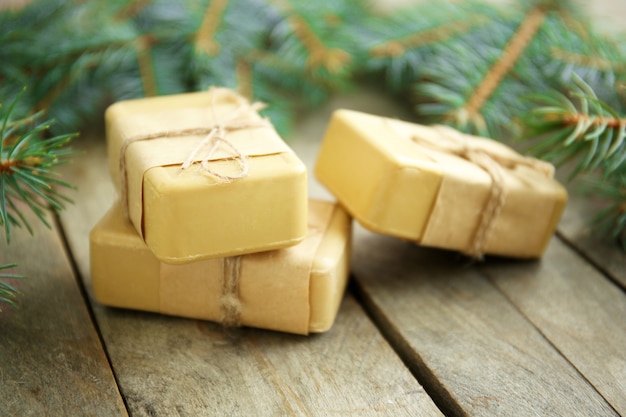 Pieces of coniferous soap and branches on wooden wall, close up view