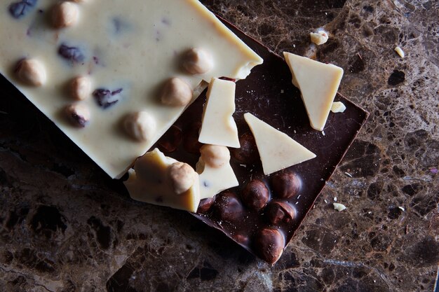 Pezzi di cioccolato fondente e bianco isolati su uno sfondo di marmo scuro