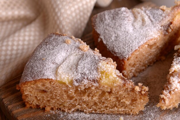 Pieces of delicious cake on cutting board on wooden table