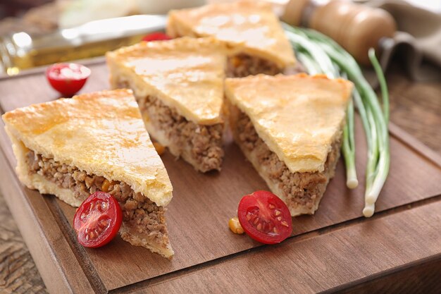 Pieces of delicious meat pie on wooden board