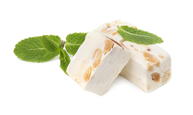 Pieces of delicious nougat and mint on white background