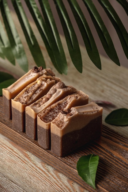 Кусочки ароматного кофе и шоколадного мыла на деревянном фоне Концепция натурального эко-мыла и косметики