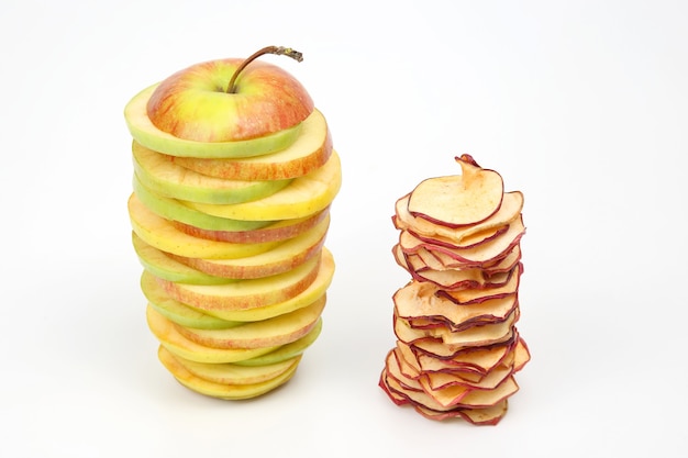 Pieces of fresh and dried apples stacked in a pyramid on a white background