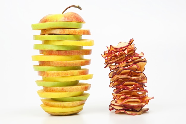 Pieces of fresh and dried apples stacked in a pyramid on a white space