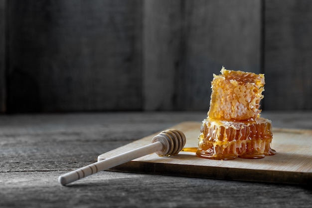 Photo pieces of fresh honeycomb with honey and a wooden stick