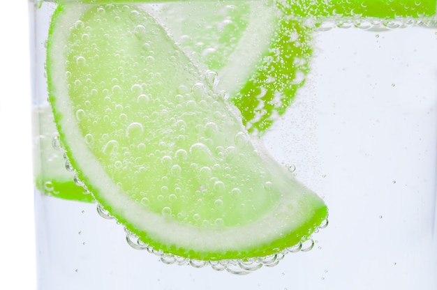 Pieces of fresh juicy lime sink into crystal clear water.