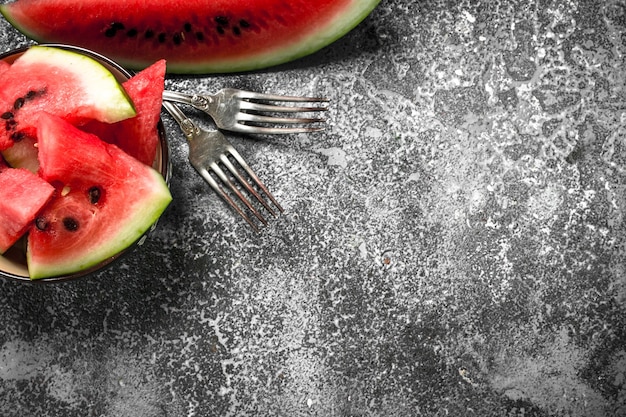 Pieces of fresh watermelon in a bowl on rustic table.