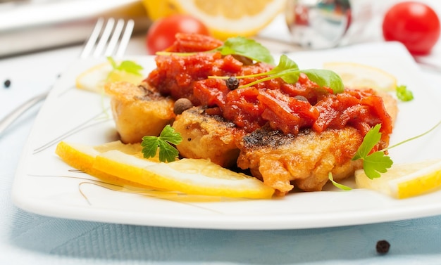 Pieces of fried fish in tomato sauce with carrots