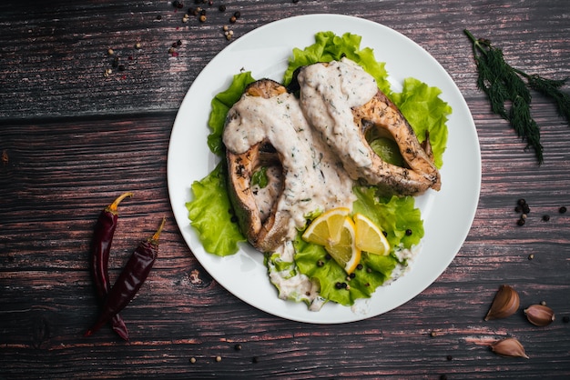 Pieces of fried red fish with cream sauce on a white plate