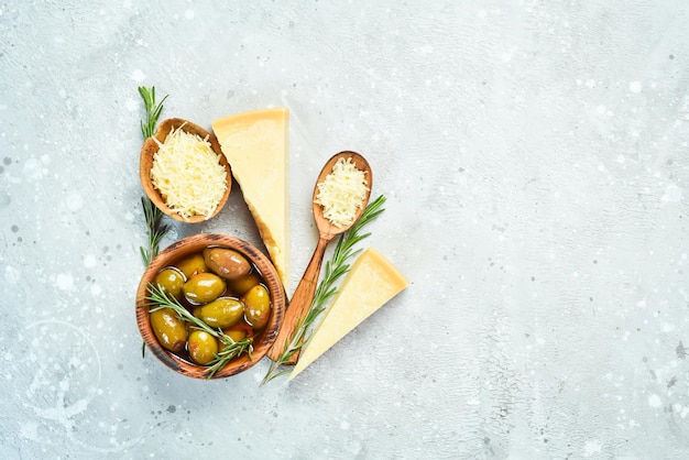 灰色の石の背景にハードチーズとオリーブのかけら。食品の背景。テキスト用の空きスペース。
