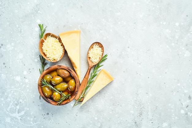 pieces of hard cheese and olives on a gray stone background. food background. free space for text.