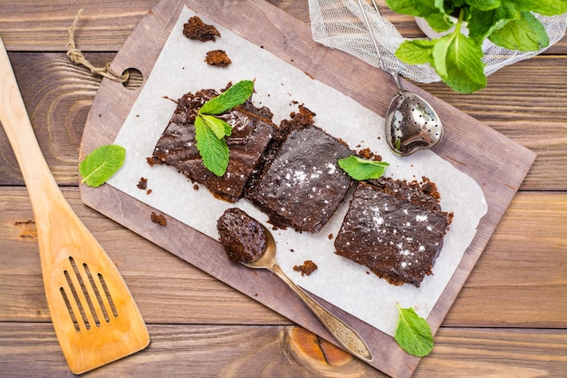Pieces of homemade chocolate brownies with leaves of mint, Top view