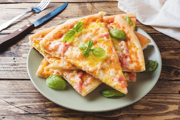 Pieces of homemade pizza on a plate on a wooden table.