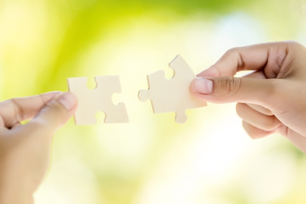 Pieces of jigsaw puzzle in woman's hands