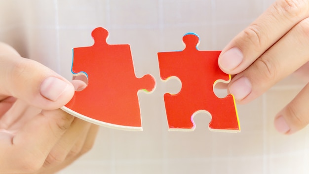 Pieces of jigsaw puzzle in woman's hands