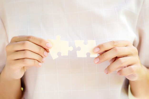 Pieces of jigsaw puzzle in woman's hands