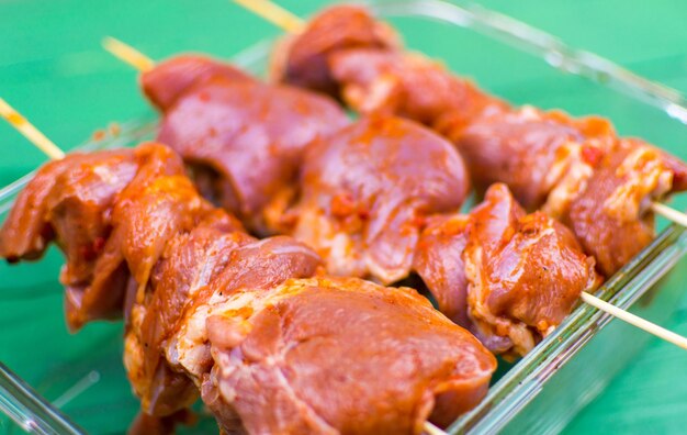 Pieces of marinated meat in seasonings on wooden skewers