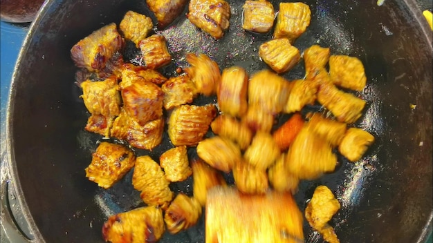 肉片は熱いフライパンで焼けるように暑い油で揚げられます 学士号の朝食は食べ物を簡単に調理できます 料理人は木製のへらで肉を混ぜます マクロのクローズアップビュー 肉を揚げるコンロの上