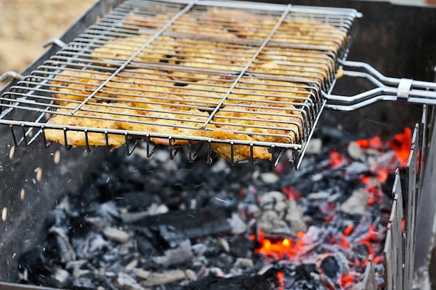 Pieces of meat laying on the mesh for a barbecueBurning coals in the grill