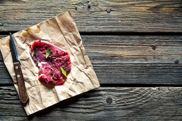 Pieces of meat, steak with spices on a wooden background. Food