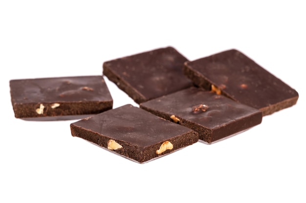 Кусочки темного шоколада с орехами в куче, изолированные на белом фоне. фото высокого качества