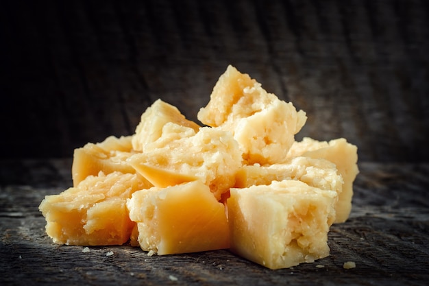 Pieces of parmesan cheese on dark background closeup