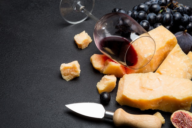 Pieces of parmesan or parmigiano cheese, wine and grapes