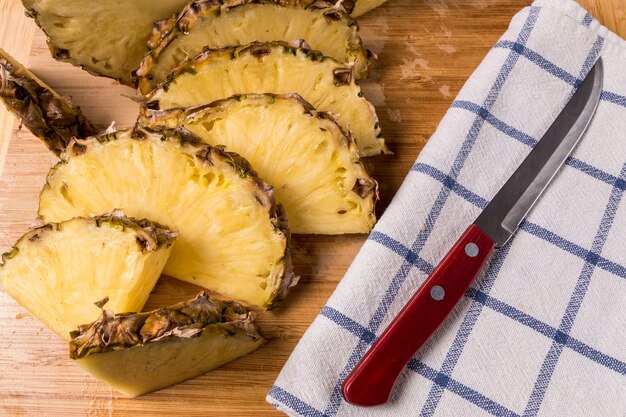 Pieces of pineapple fruit over old wooden board.