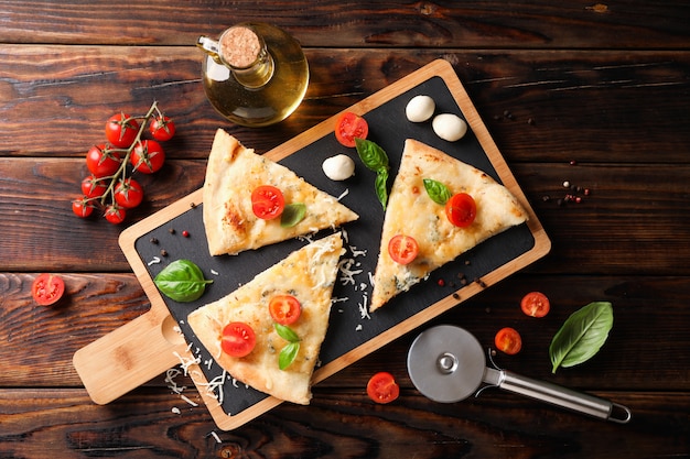 Pieces of pizza and ingredients on wooden background