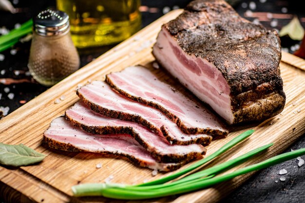 Pieces of pork lard on a cutting board with green onions and bay leaves